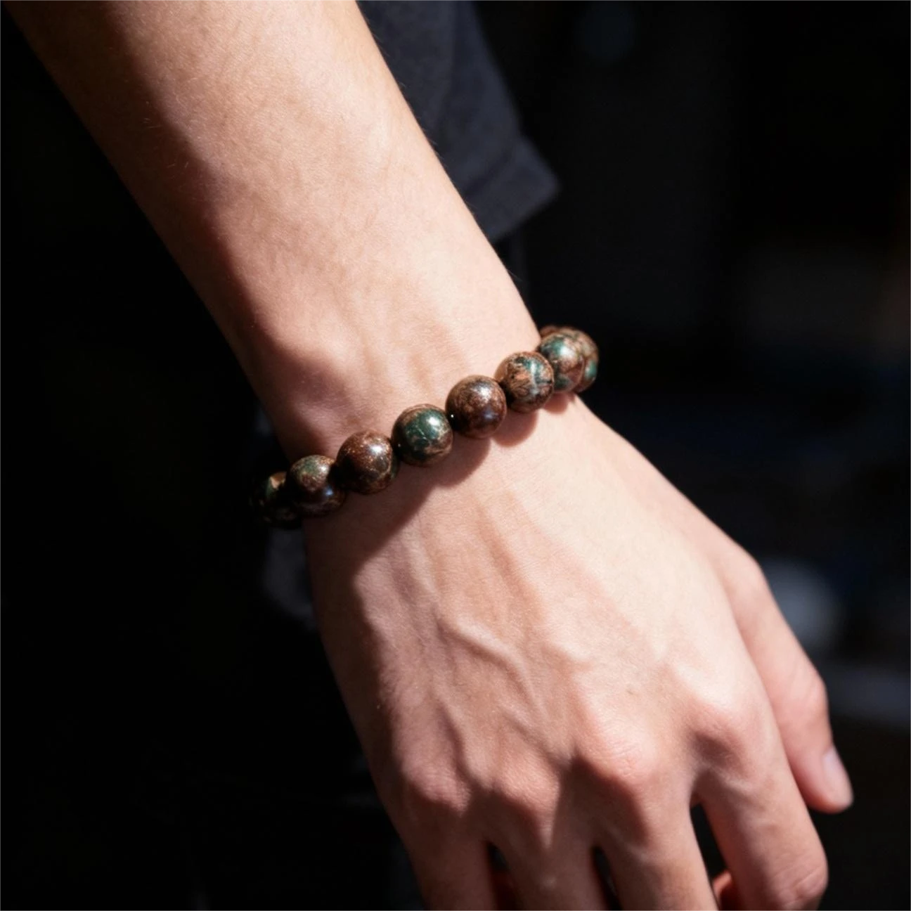 jimeng-2025-11-18-5227-将图1手串佩戴在模特的手腕上，手串的珠子颜色位置不能变动， 场景：背景为暗色调、....png